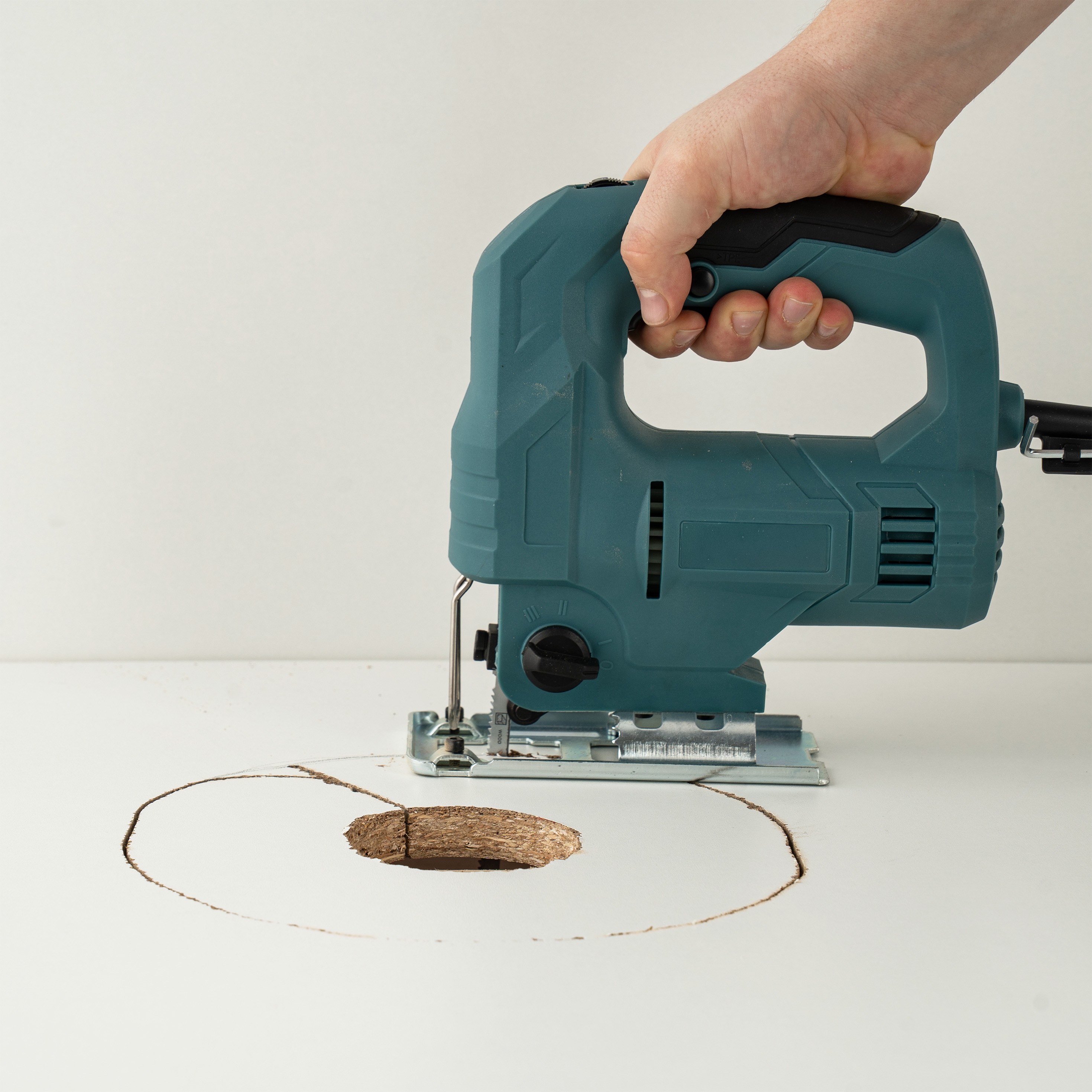 Groot gat in plafond zagen met decoupeerzaag voor het plaatsen van een LED-inbouwspot