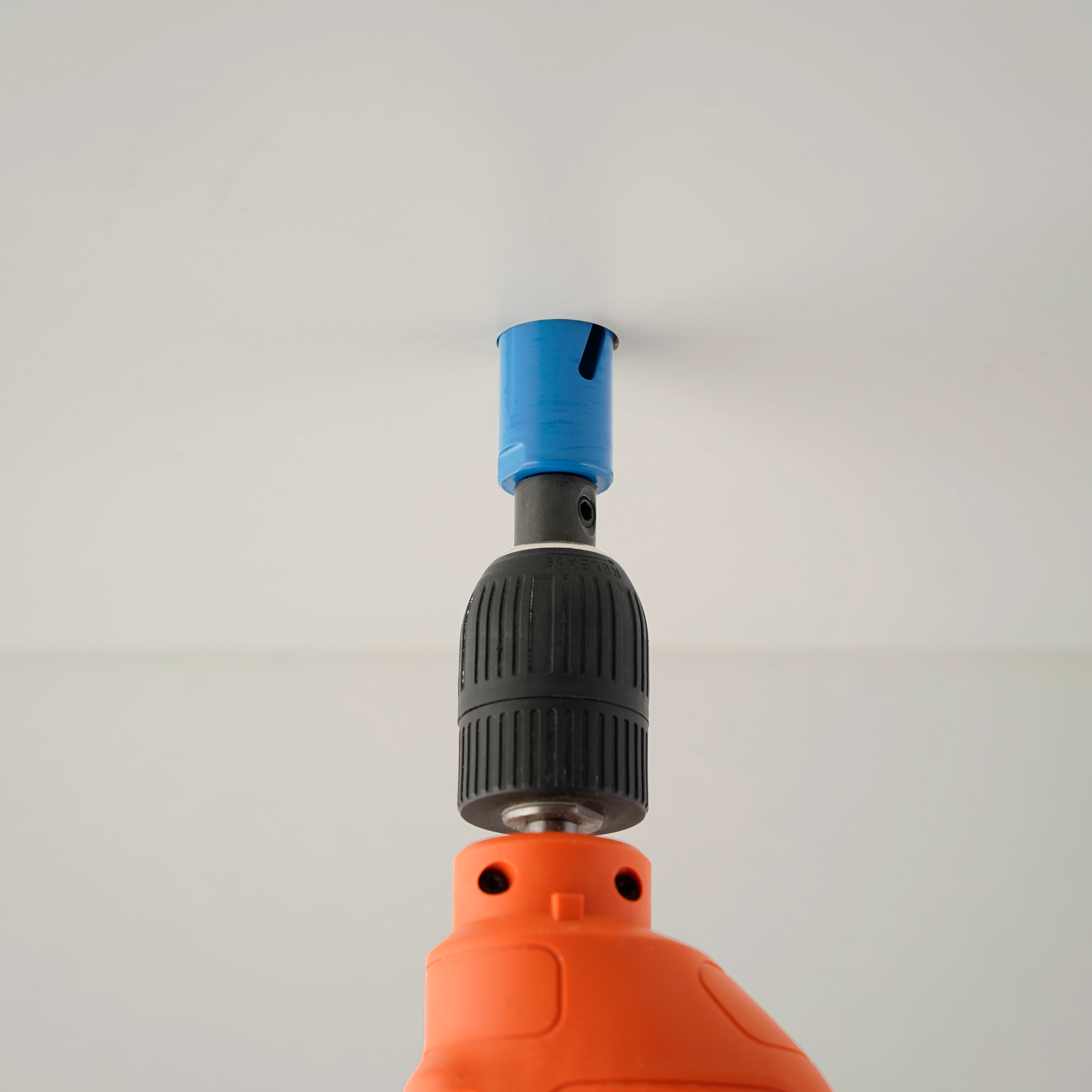 Klein gat in het plafond boren met gatenzaag voor het plaatsen van een mini LED-inbouwspot