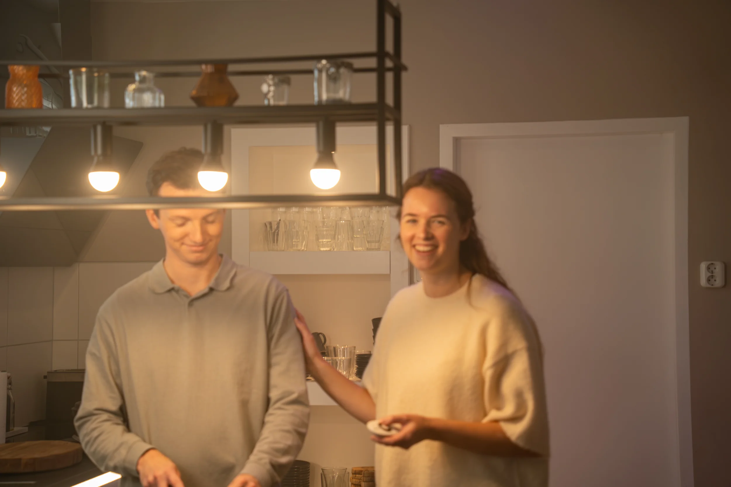Drie lichts hanglamp boven eettafel met warm sfeerlicht in moderne keuken met drie zichtbare lampen